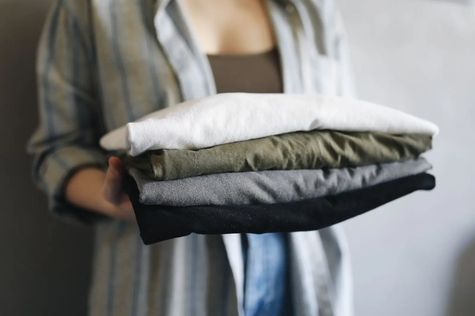 Hands holding a stack of folded clothes