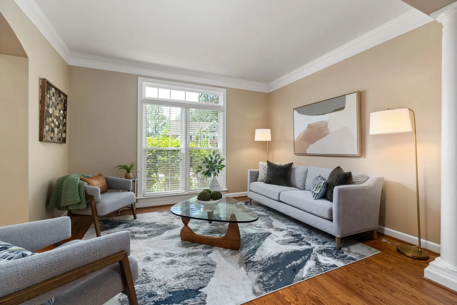A bright, tidy living room with a sofa, a rug and a glass coffee table